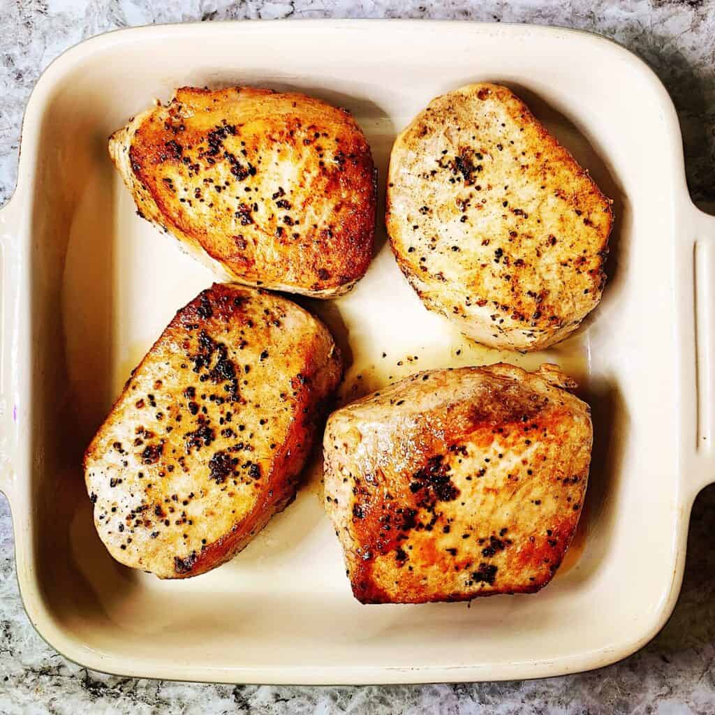 A casserole dish with four boneless pork loin chops