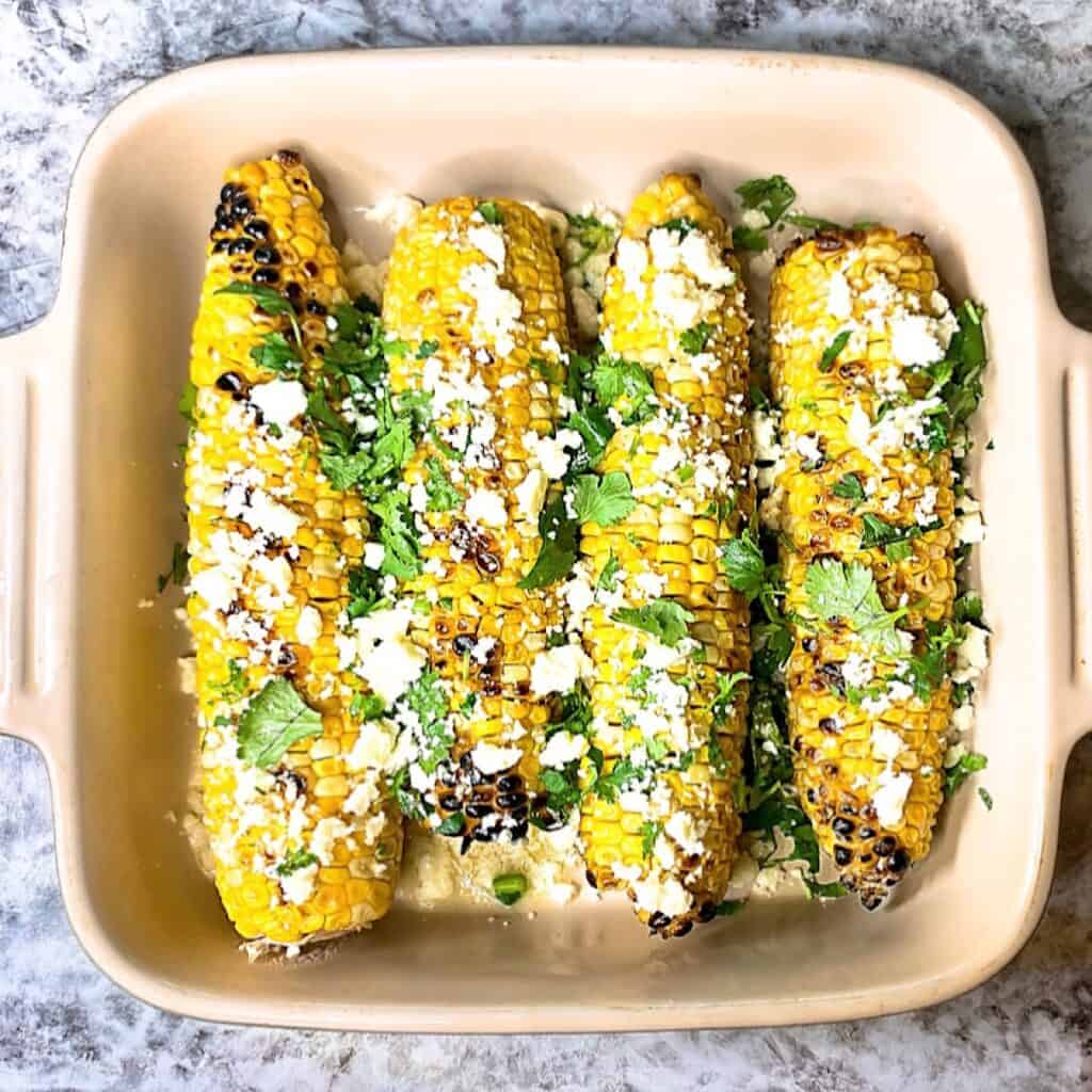 Mexican street corn in a casserole dish with all the toppings