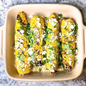 Mexican grilled corn in casserole dish with cojita cheese and cilantro