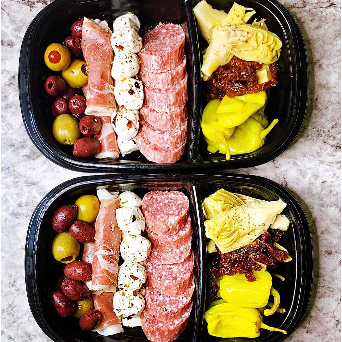 Two meal prep containers with salami, peppers, mozzarella, prosciutto, olive medley, artichoke, sundried tomatoes