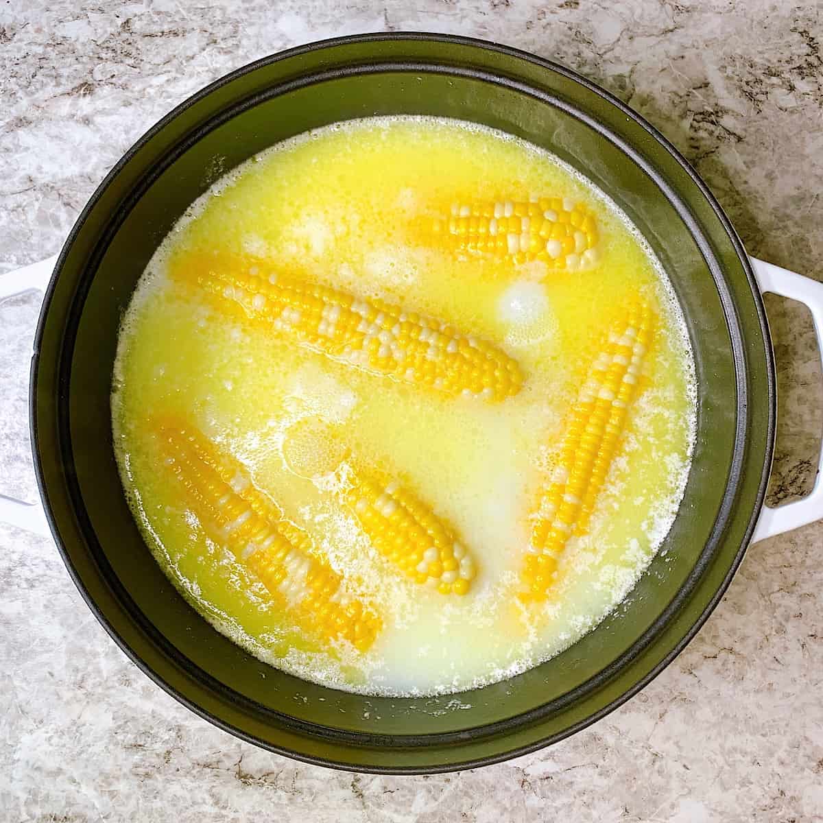 Large Staub white pot filled with boiled corn butter and milk