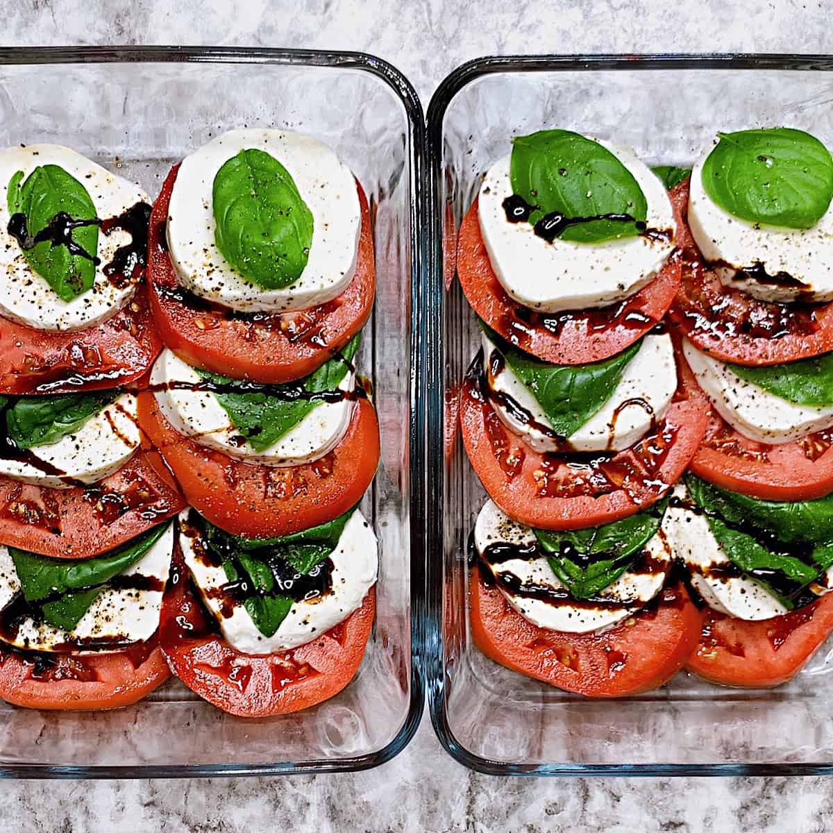 Two meal prep containers with sliced tomato mozzarella cheese basil and balsamic glaze
