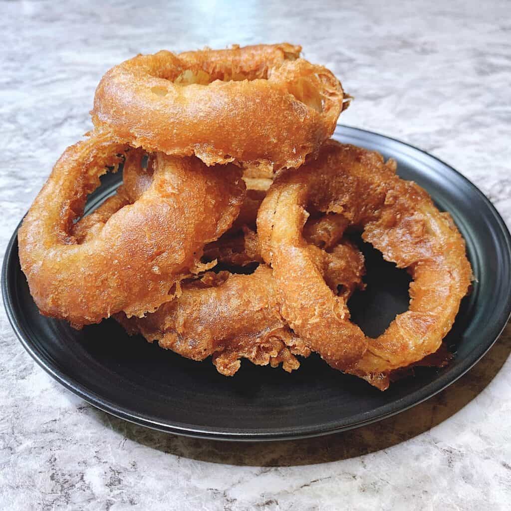 Onion rings stacked on a black plate
