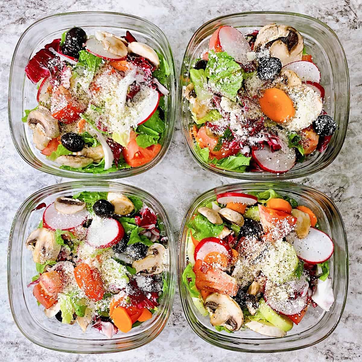 Four glass tupperware bowls filled with italian salad ingredients