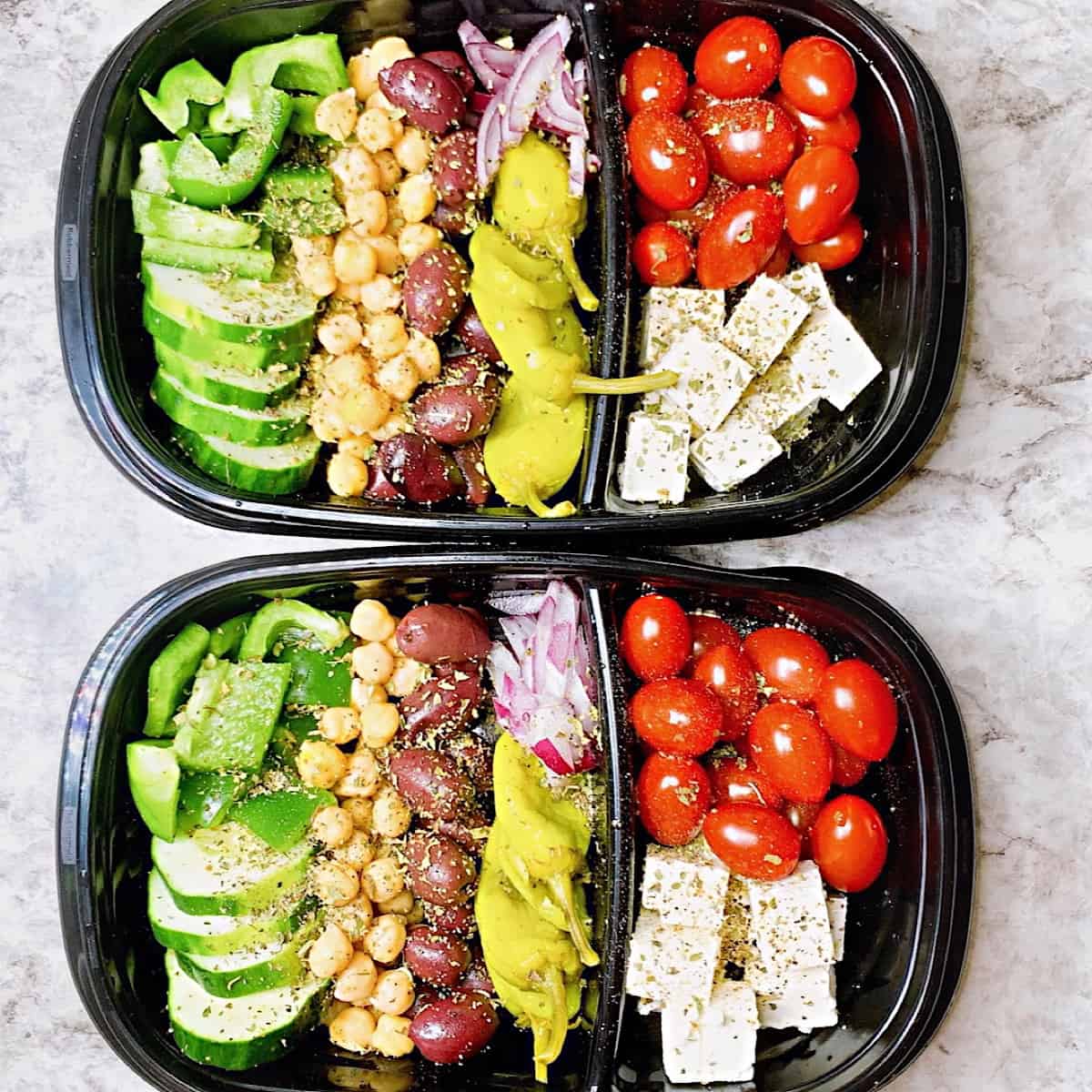 Two containers with chopped tomato feta Greek peppers cucumber chick peas kalamata onions and red onions