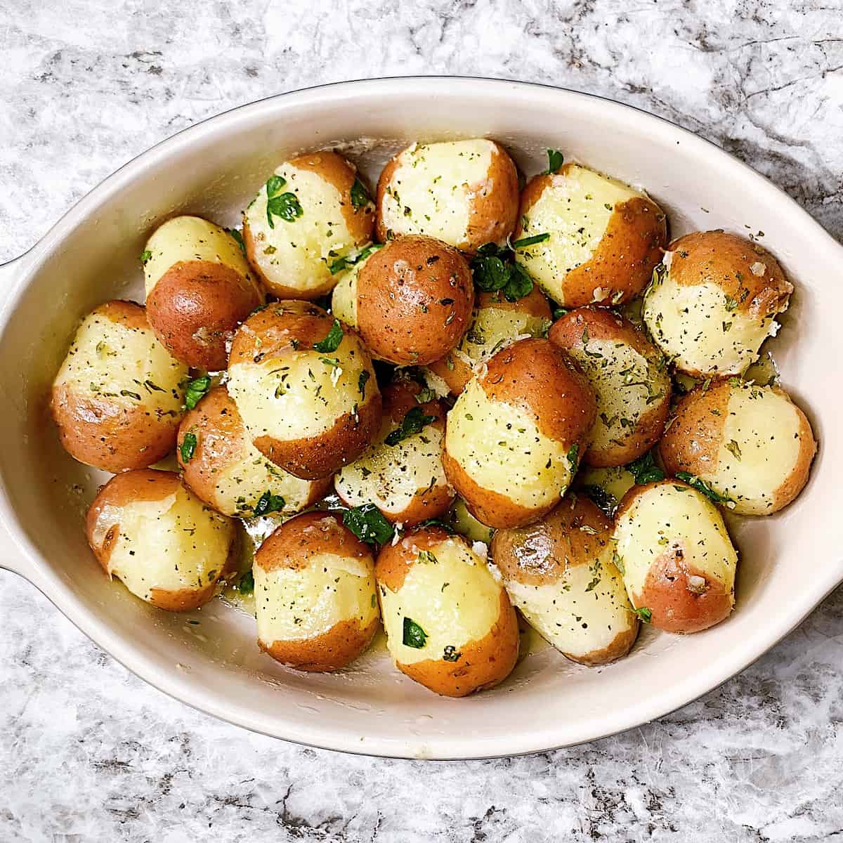 Platter with boiled red potatoes drenched in butter and topped with parsley