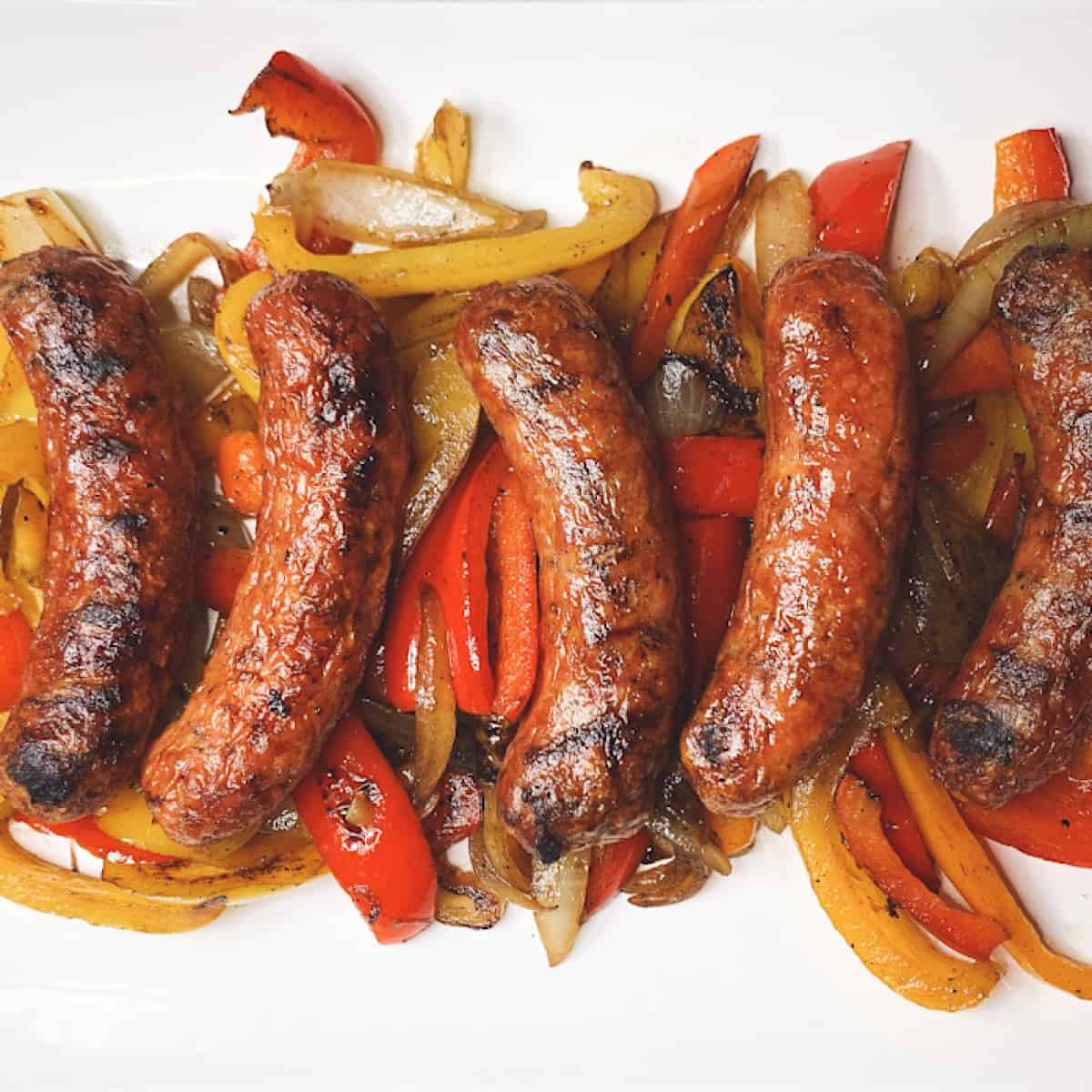 Grilled sausage peppers and onion on a white platter