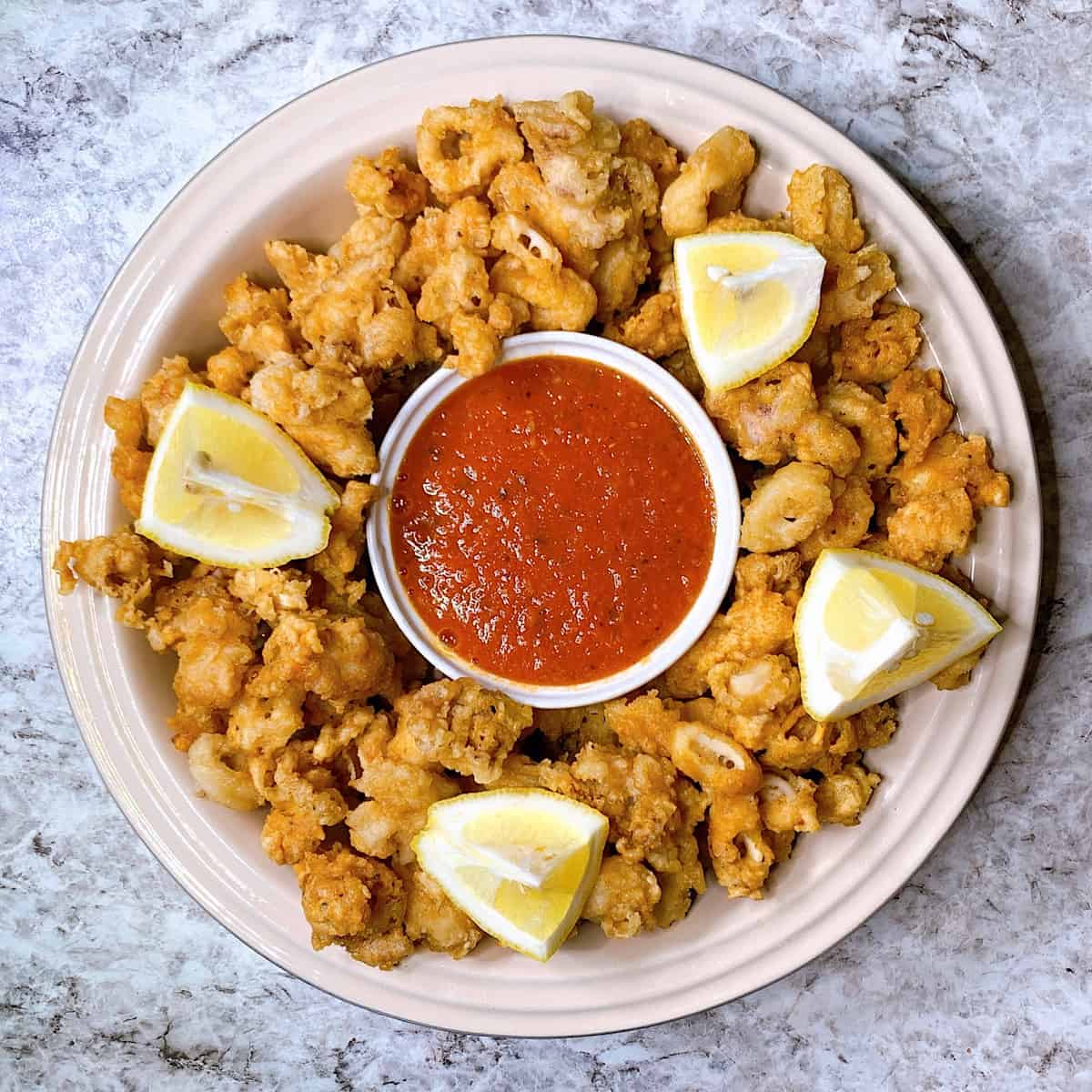 Deep fried calamari in a dish with lemon and marinara sauce