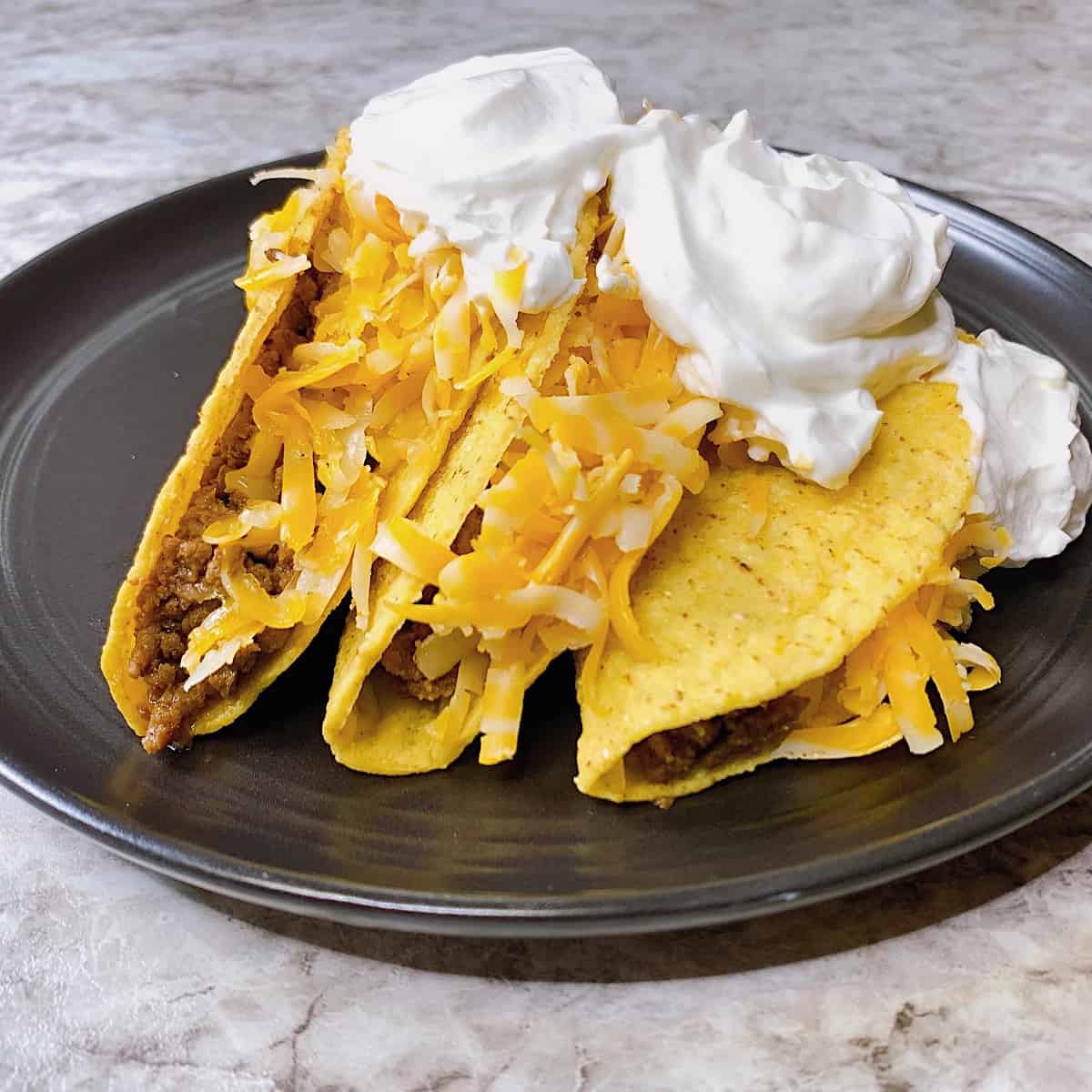 Tacos with homemade seasoning and cheese on a black plate