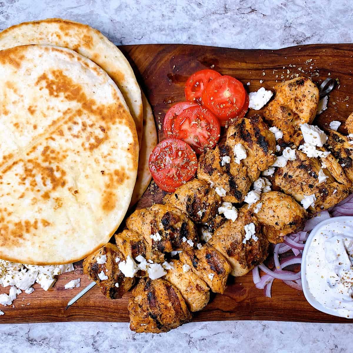Chicken souvlaki platter with pitas, grilled chicken, feta, tzatziki , tomatoes