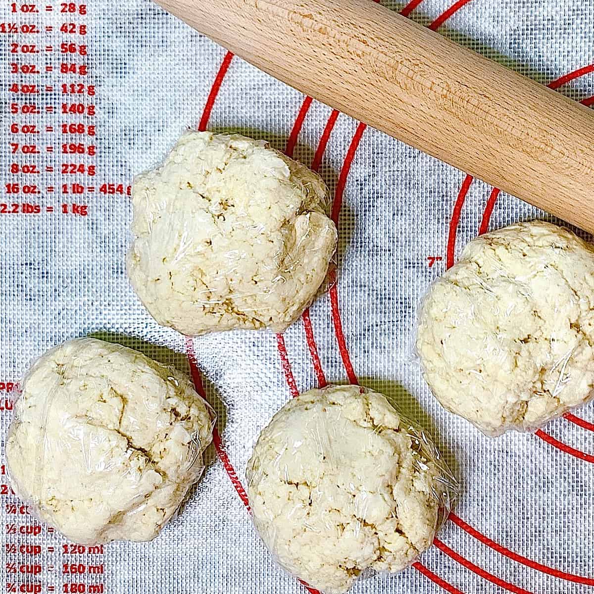Pie crust dough wrapped in cellophane on a silicone mat