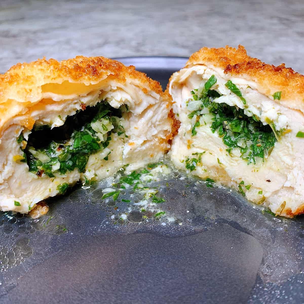 Chicke Kiev sliced open on a plate with butter and herbs melting out