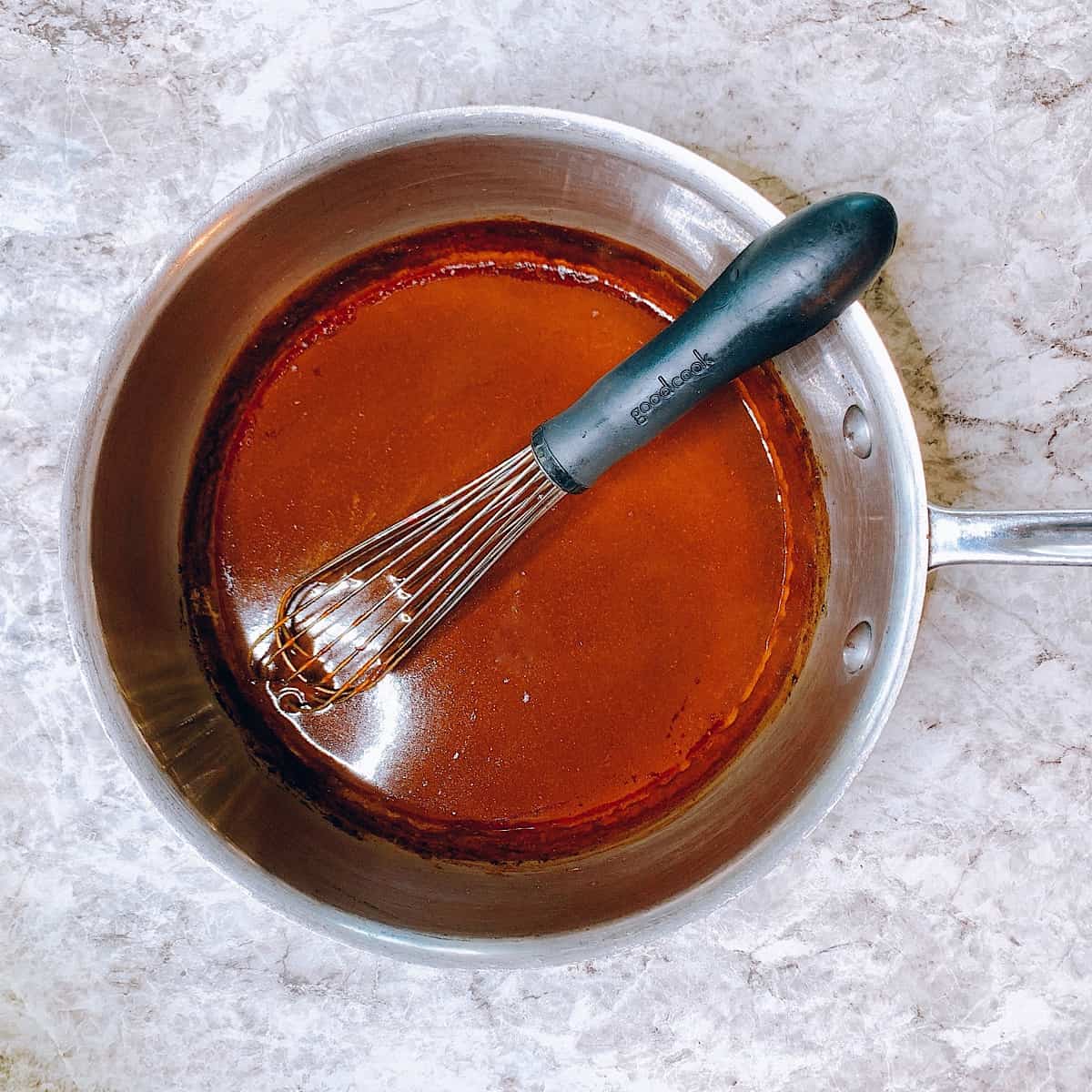 Homemade red enchilada sauce in sauce pan with whisk