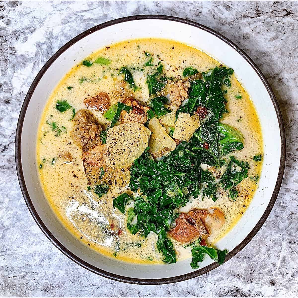 Bowl of Zuppa Toscana soup topped with bacon and kale