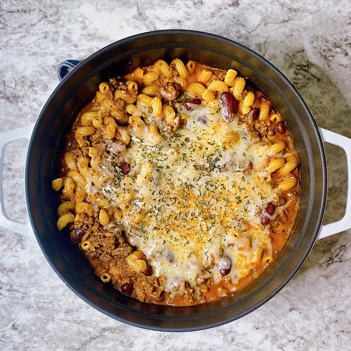 Chili Mac topped with cheese and parsley in Staub pot