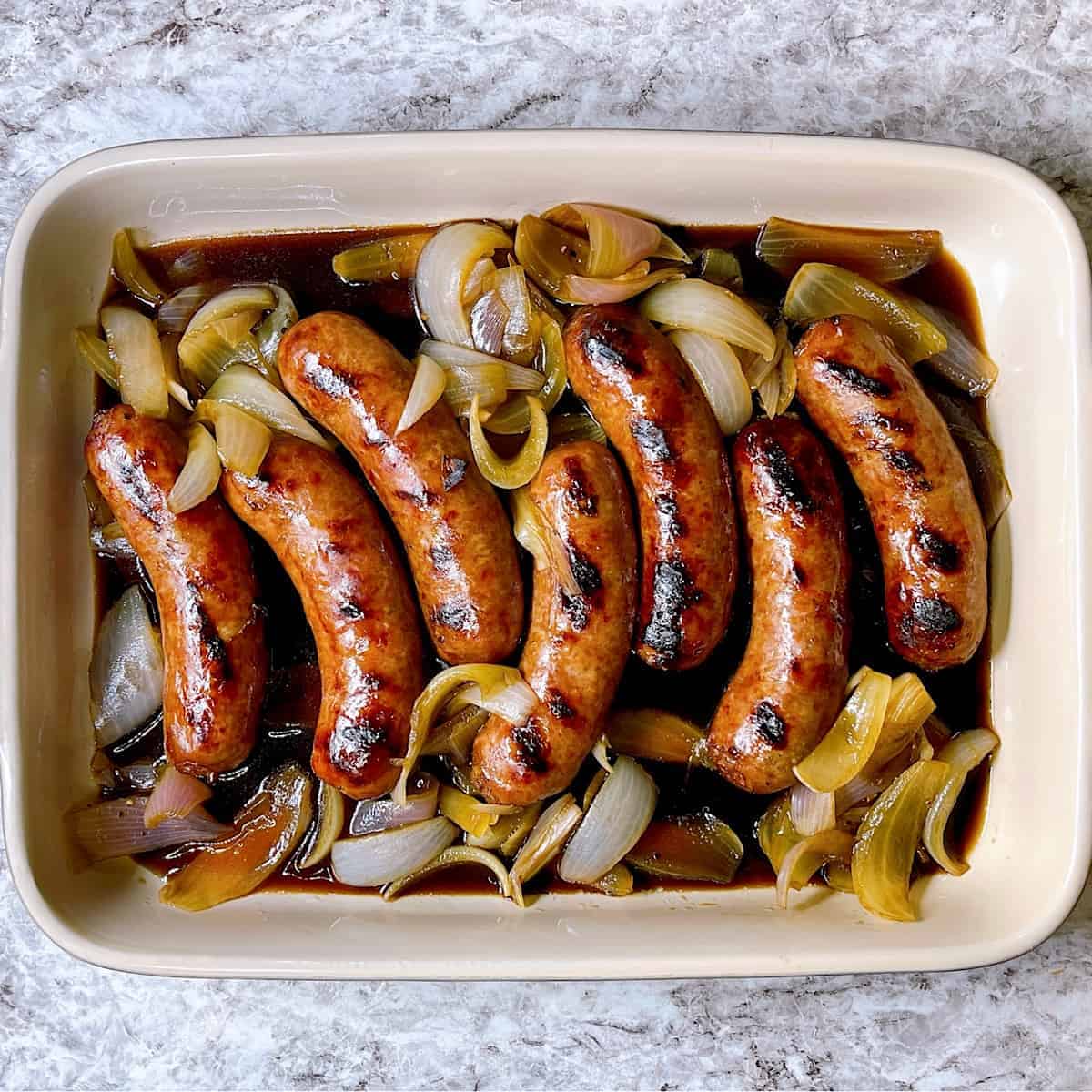 Guinness Beer Brats in casserole dish with onion