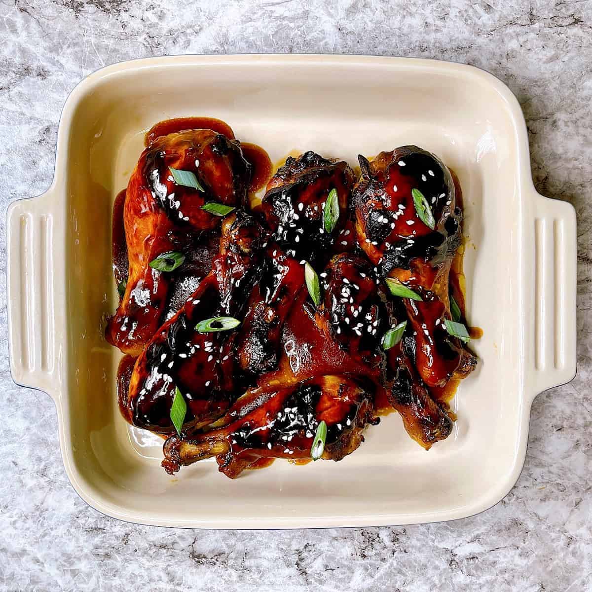 Honey Soy Drumsticks in casserole dish topped with sesame seeds and green onions