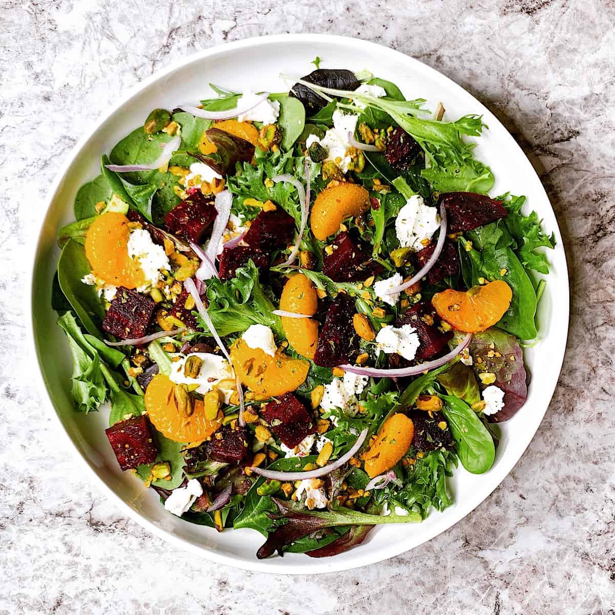 Roasted Beet and Mandarin Orange Salad in large white bowl topped with crushed pistachios