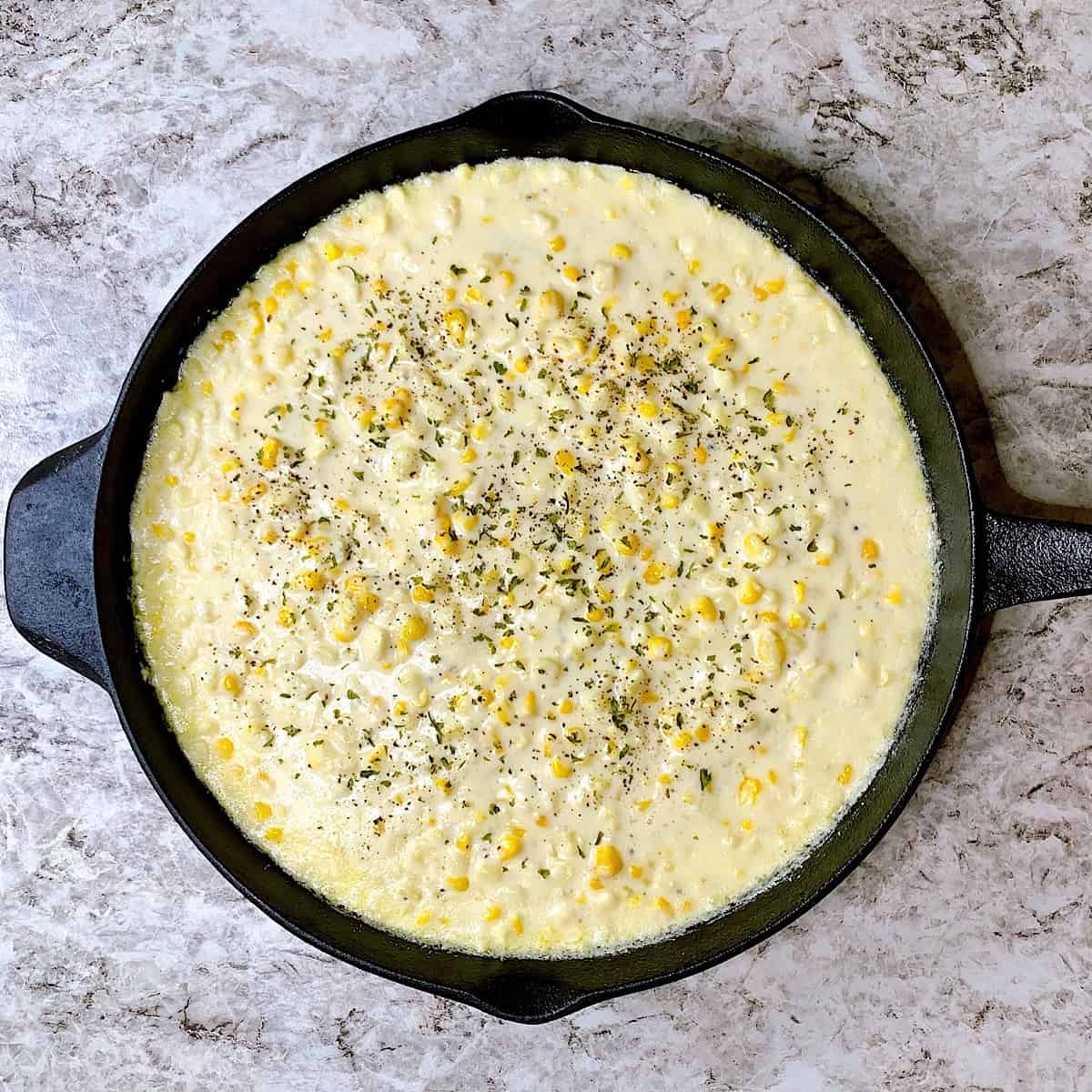 Creamed Corn in cast iron skillet topped with parsley