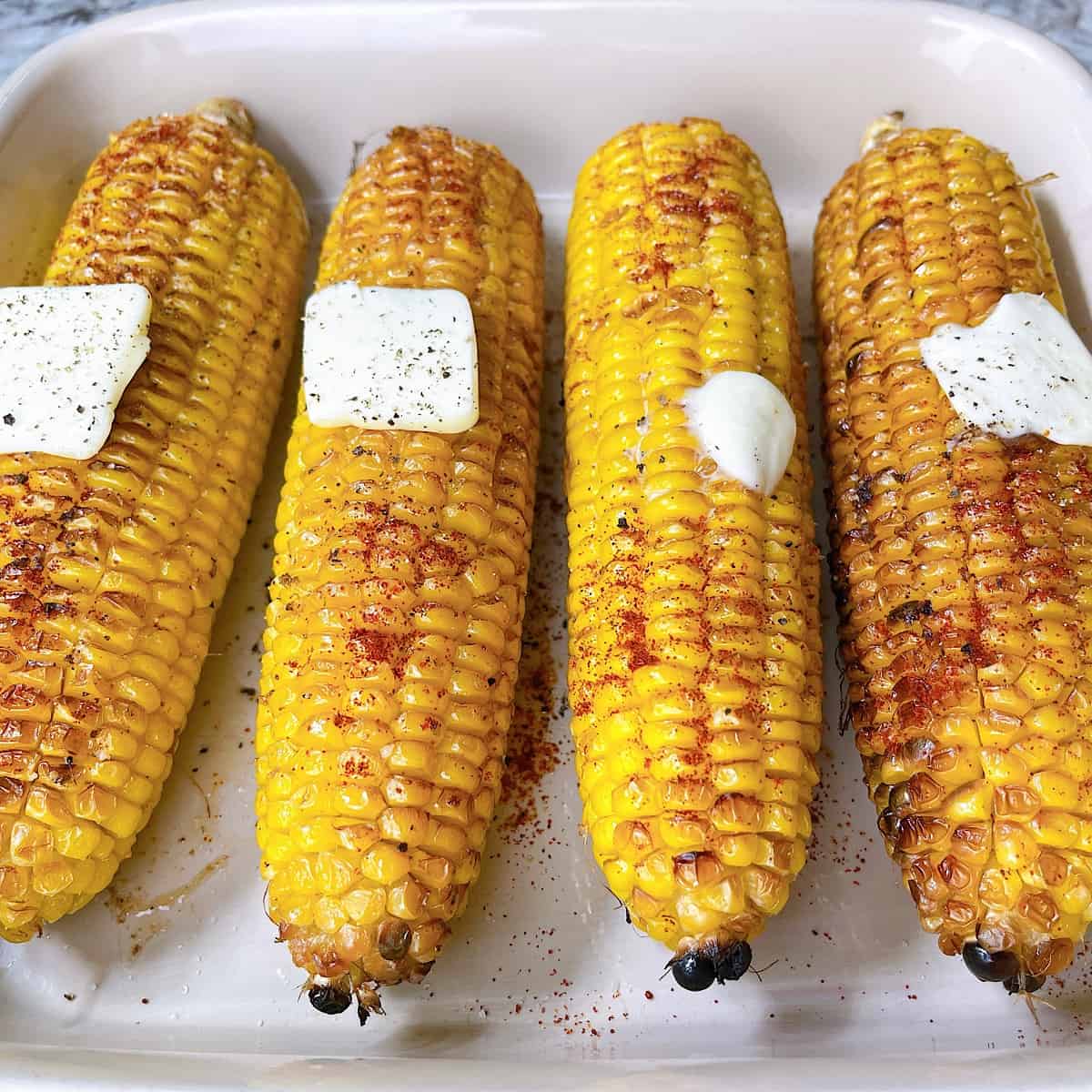 Roasted Corn in casserole dish sprinkled with paprika and topped with butter