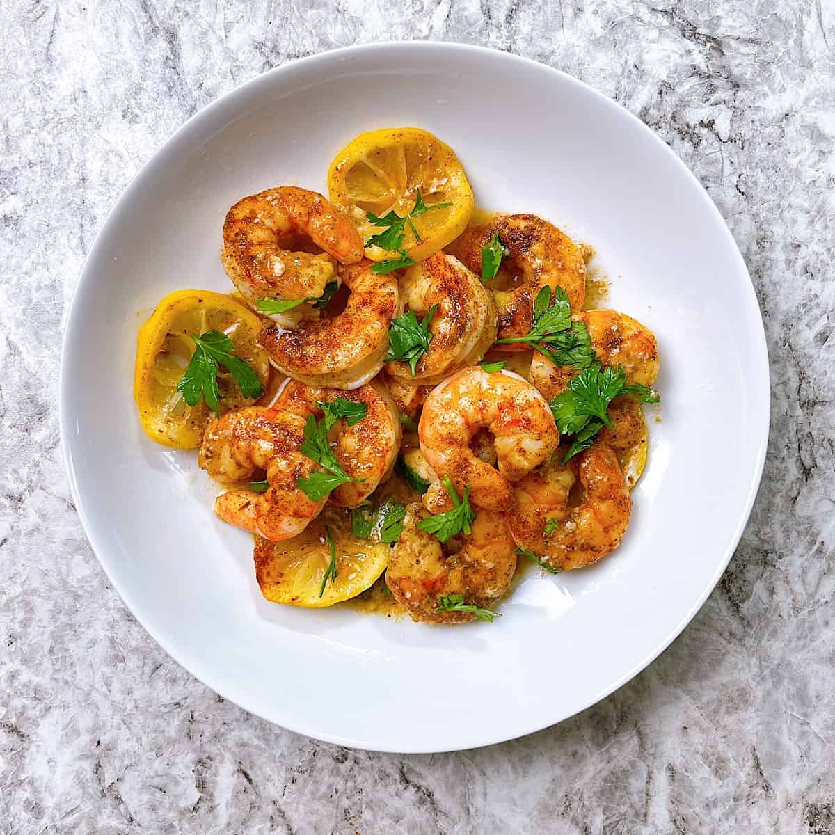 Shrimp Seasoned with Old Bay in bowl and topped with lemon and butter