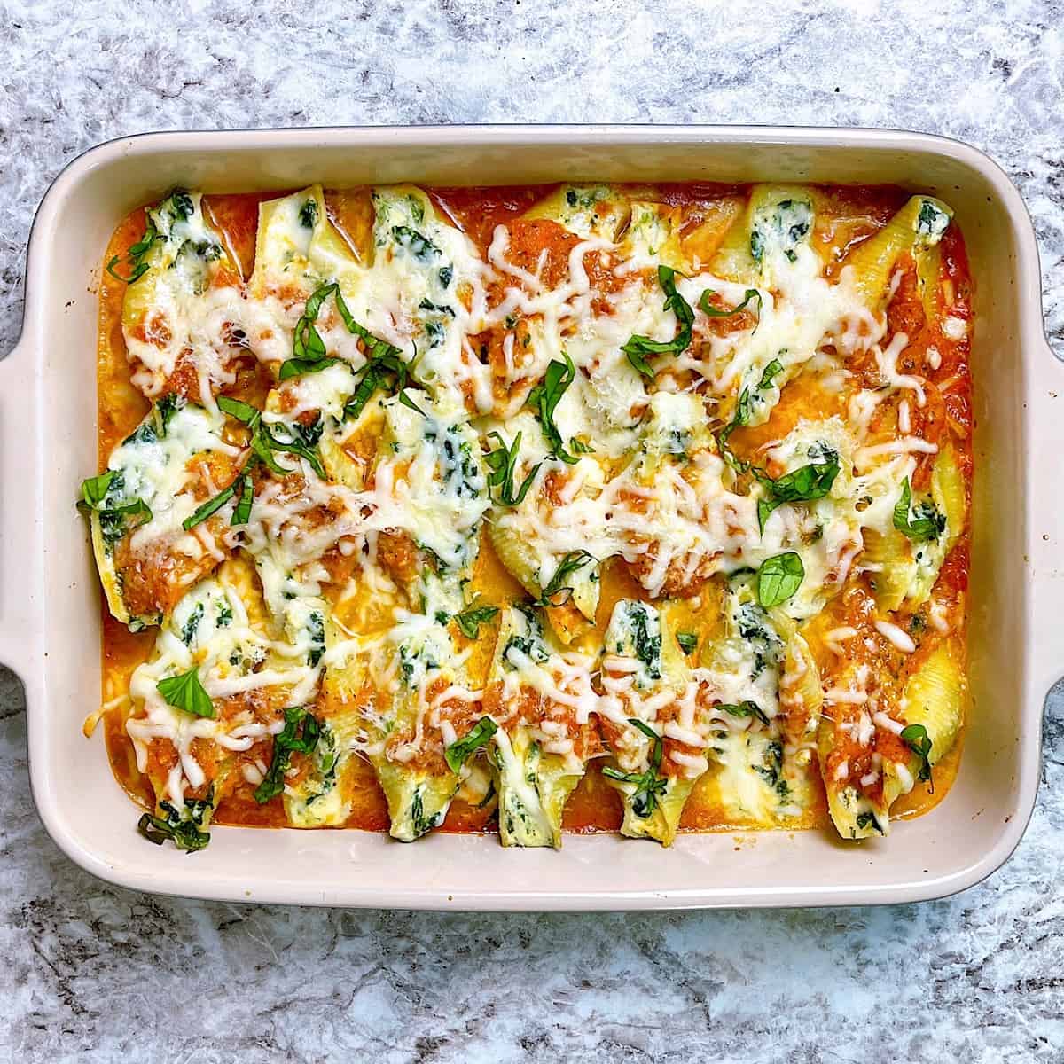 Vegetarian Stuffed Shells in casserole dish topped with Parmesan and basil