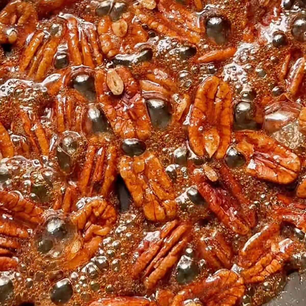 Candied pecans bubbling in a skillet.