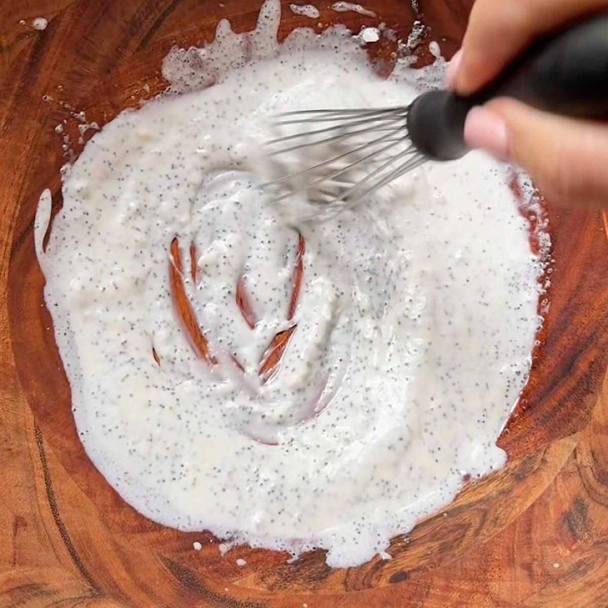 Whisking the creamy poppyseed dressing in a salad bowl.