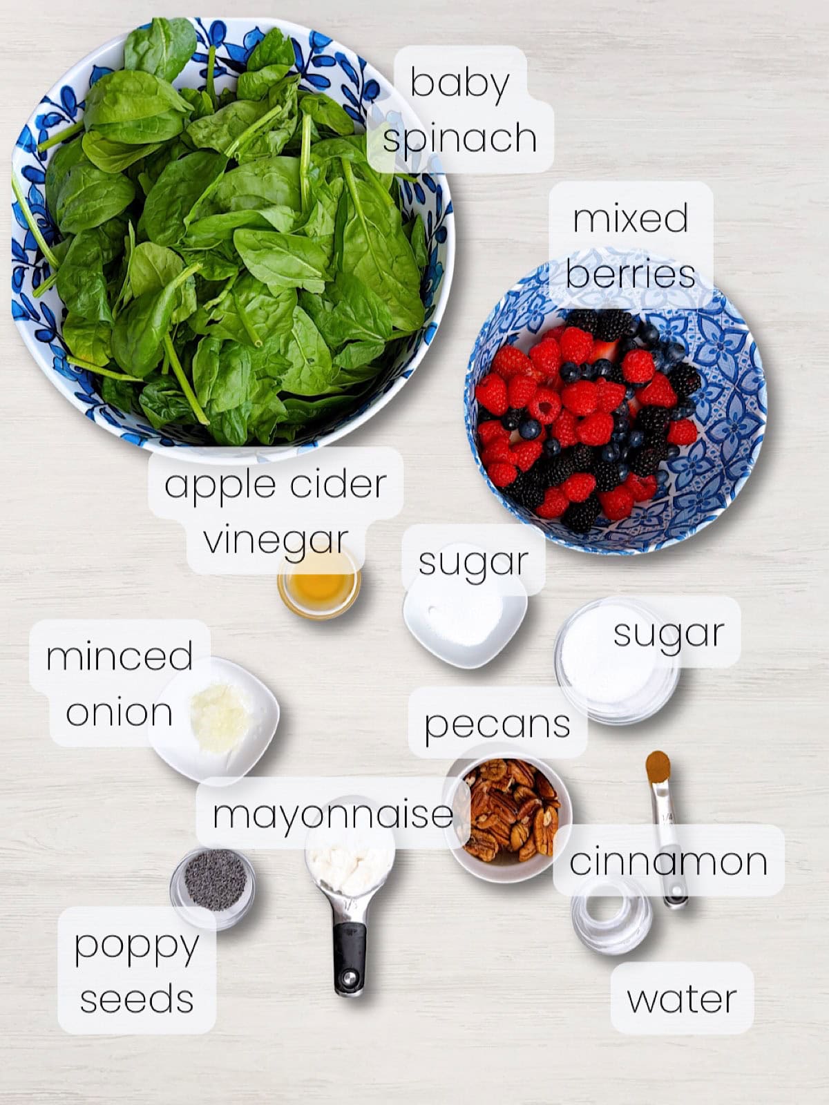 A labeled image of everything needed to make a berry spinach salad with candied pecans.