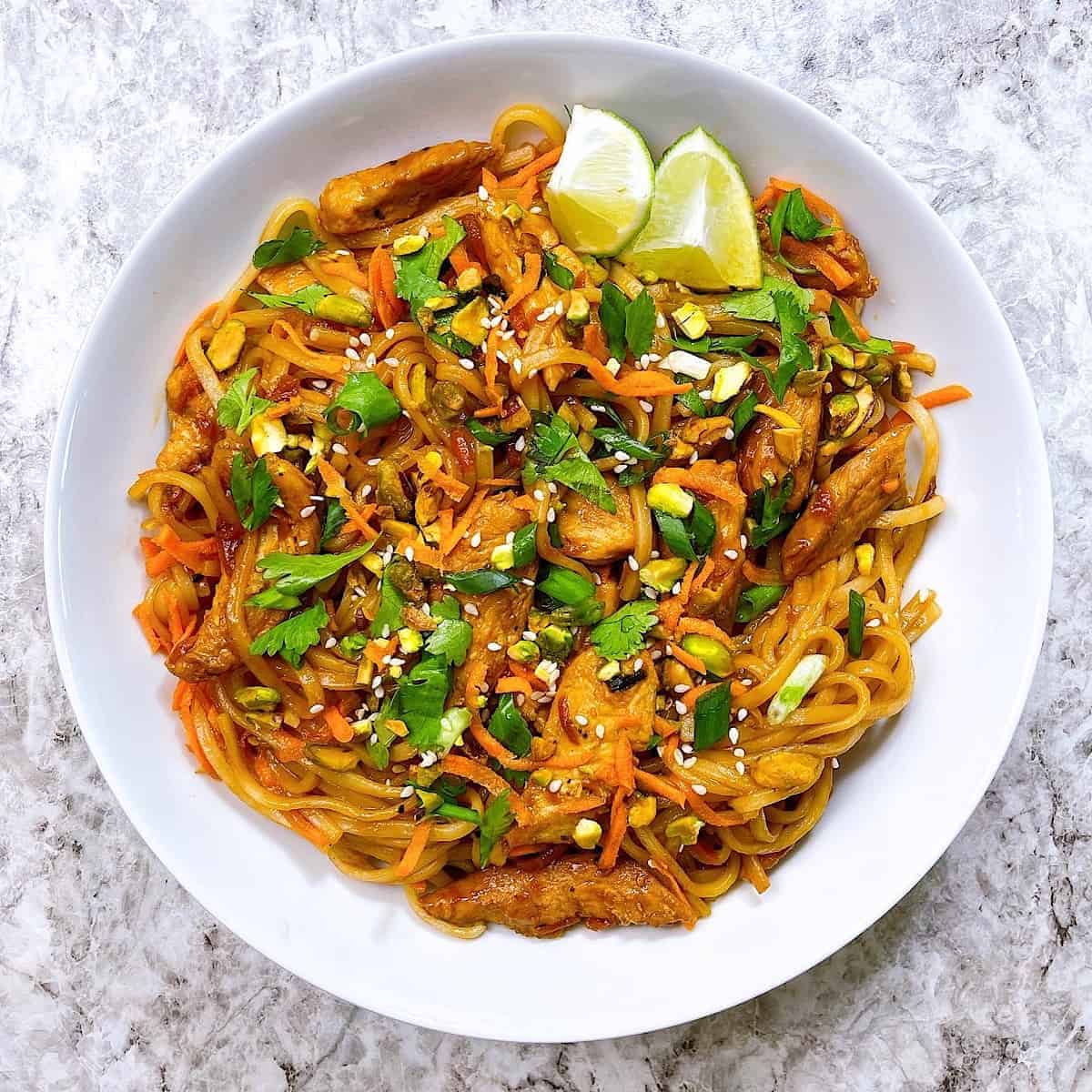 Chicken Pad Thai in white bowl topped with pistachio and cilantro