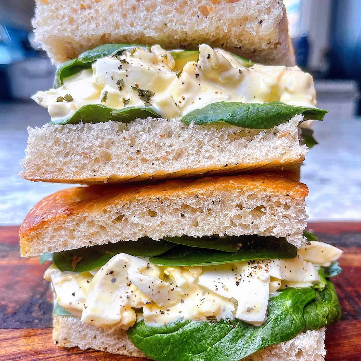 Egg Salad Sandwich​ on a wooden cutting board stacked