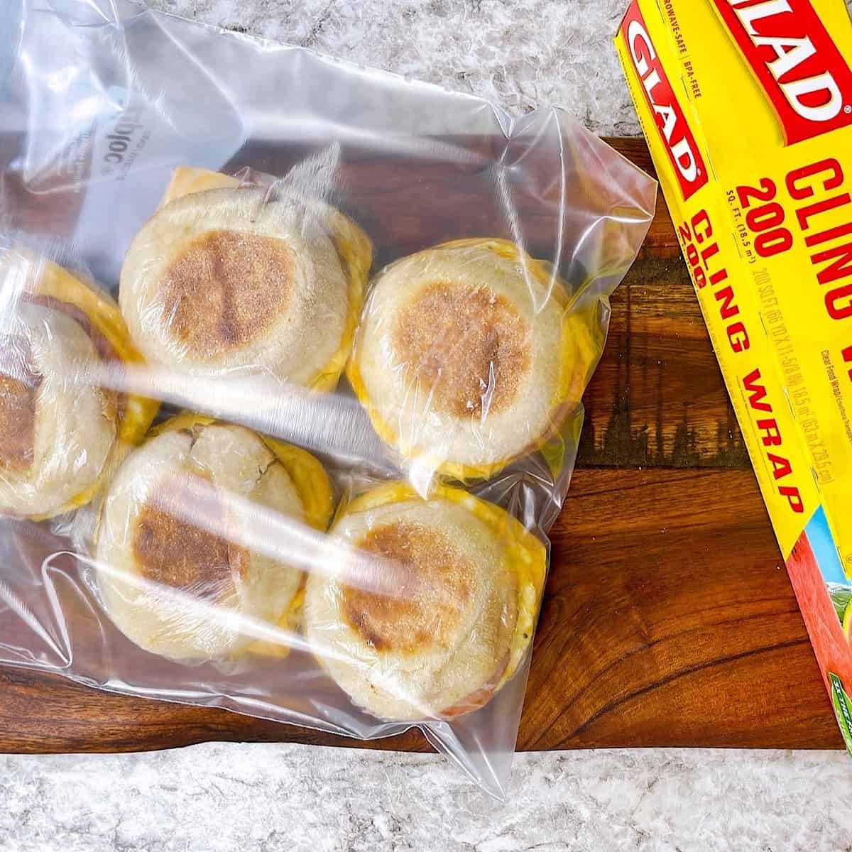 Freezer meal prep sandwiches sitting next to cling wrap in a freezer bag