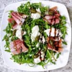 quick and easy arugula prosciutto salad close up with all the toppings and dressing