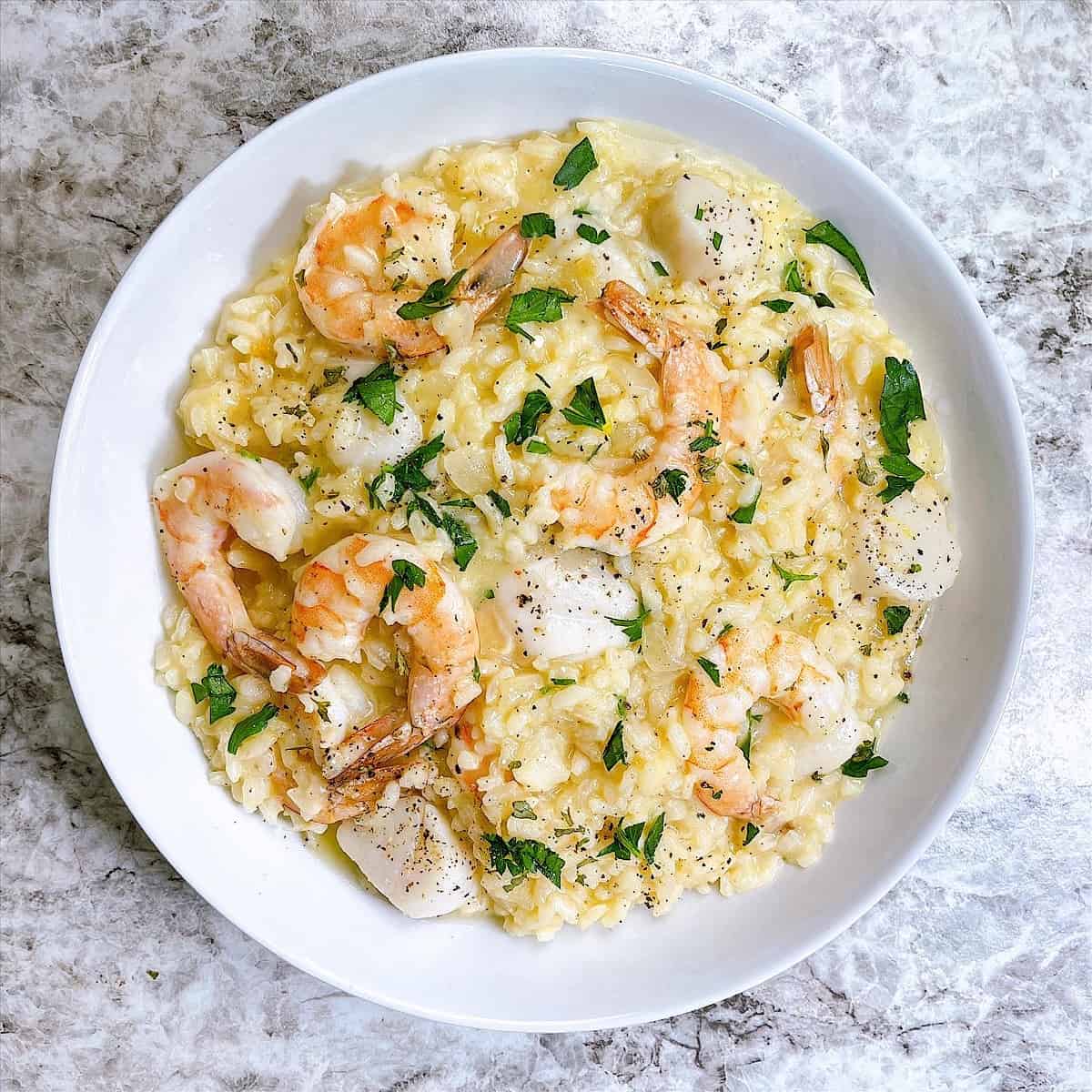 Seafood Risotto in white bowl and topped with parsley