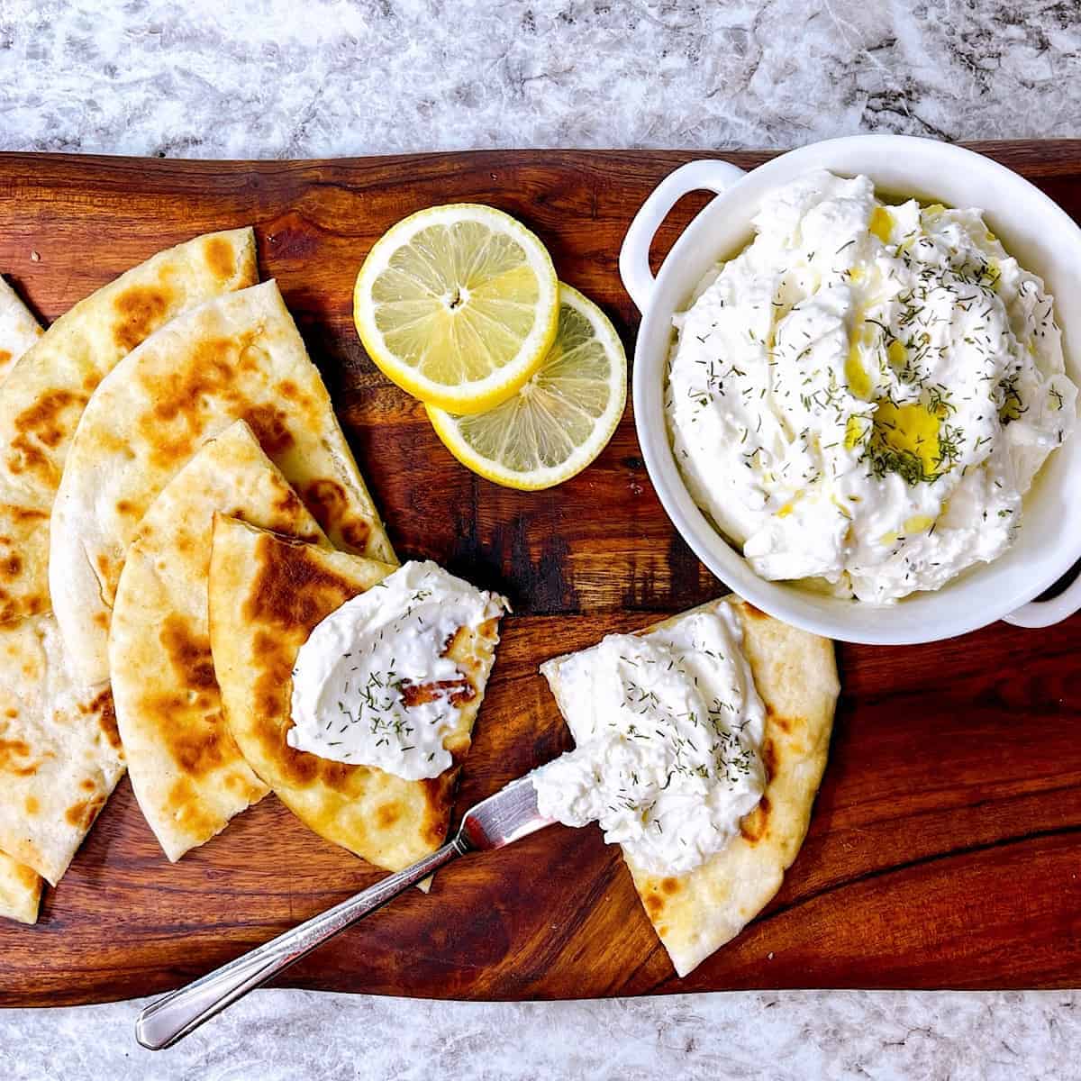 Whipped Feta Dip on cutting board with lemon and toasted pita