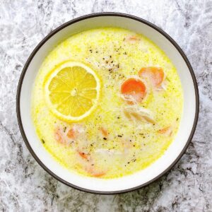 Bowl of avgolemono soup topped with lemon