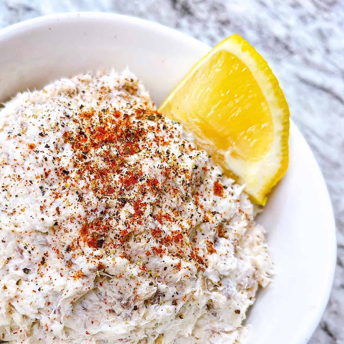 Smoked Fish Spread in small white bowl topped with lemon and paprika