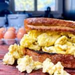 Front facing scrambled egg sandwich with a carton of eggs in the background.