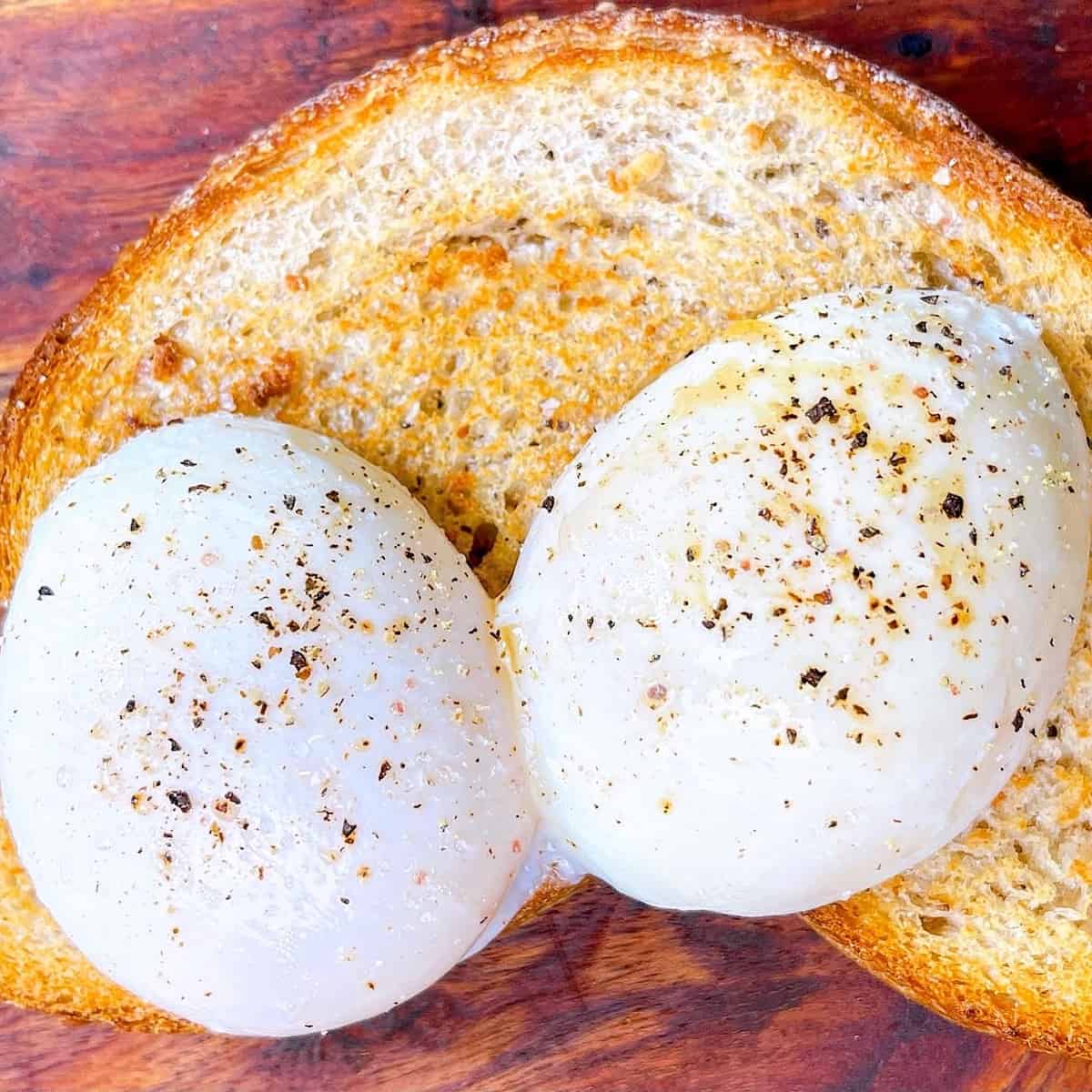 Poached eggs whole on wooden cutting board