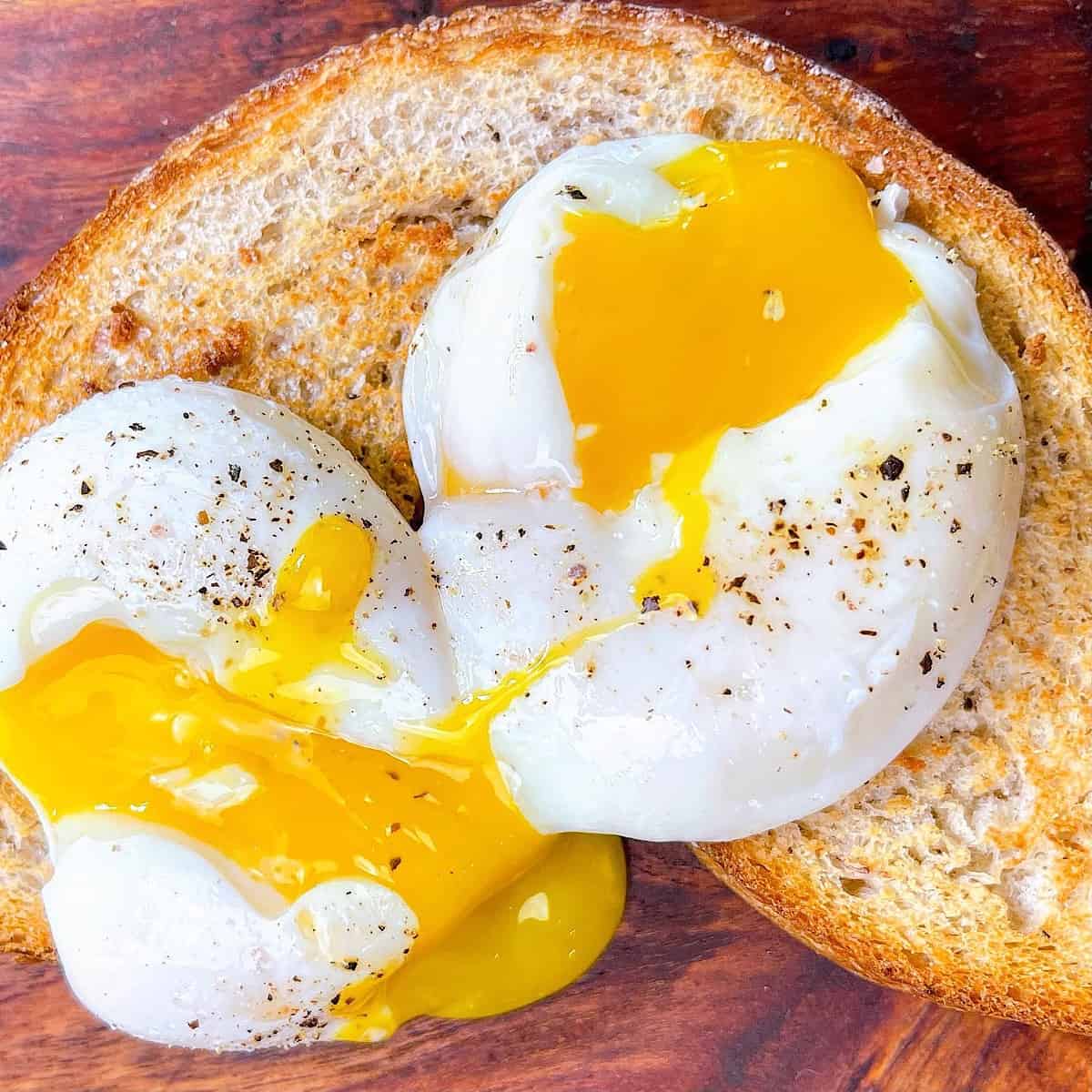 Poached eggs cut open on toast topped with salt and pepper