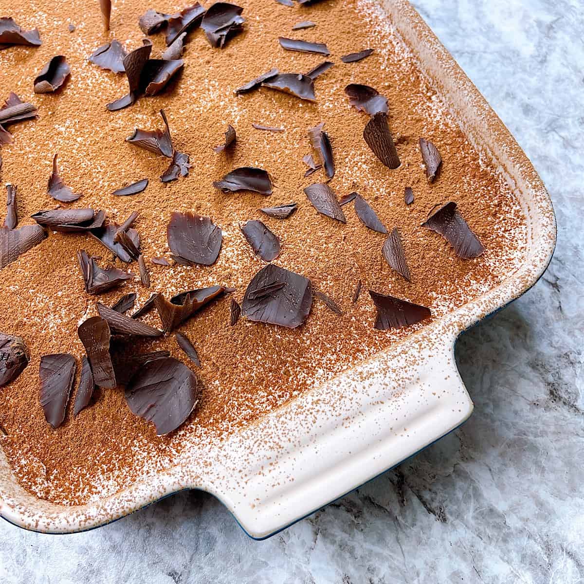 Tiramisu in casserole dish topped with shaved chocolate