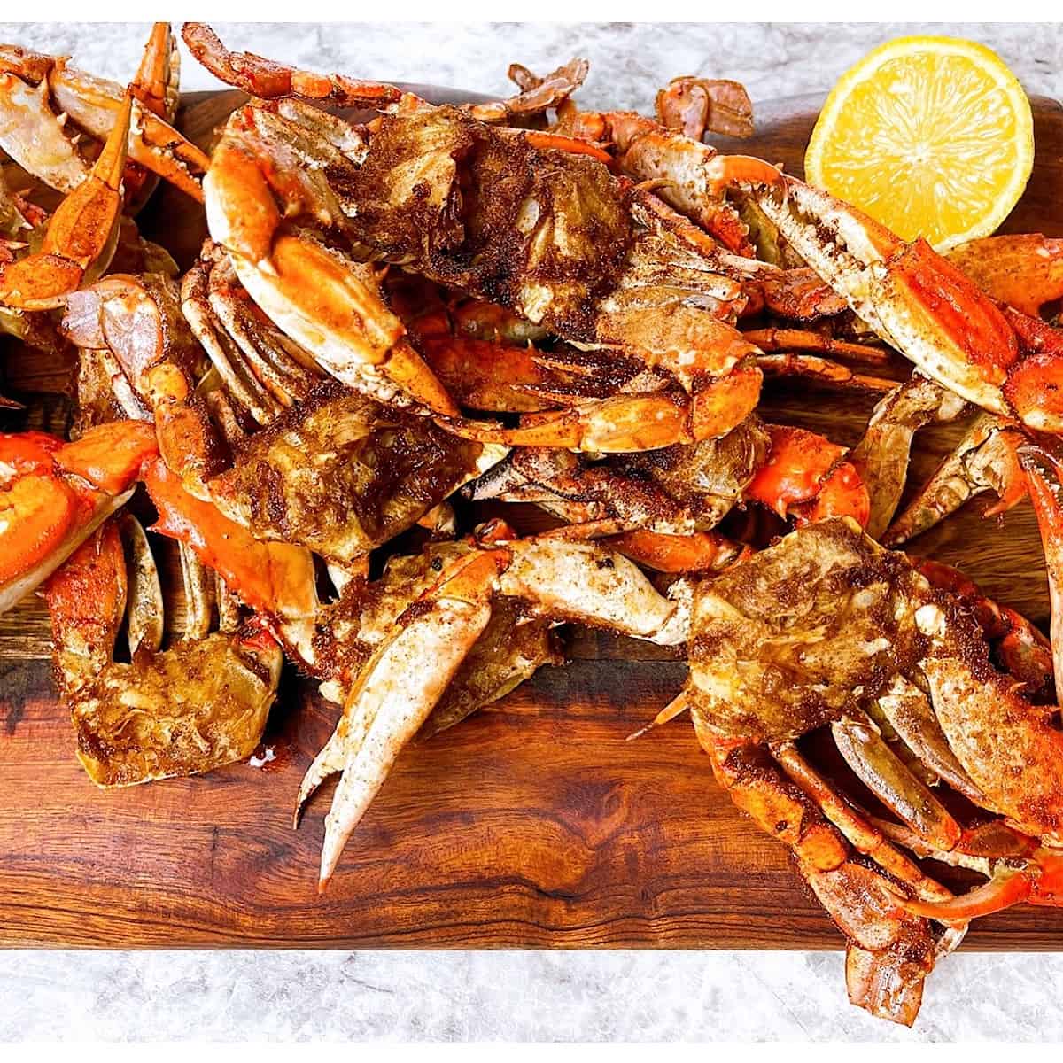 Platter of barbecued crabs on wooden cutting board with lemon