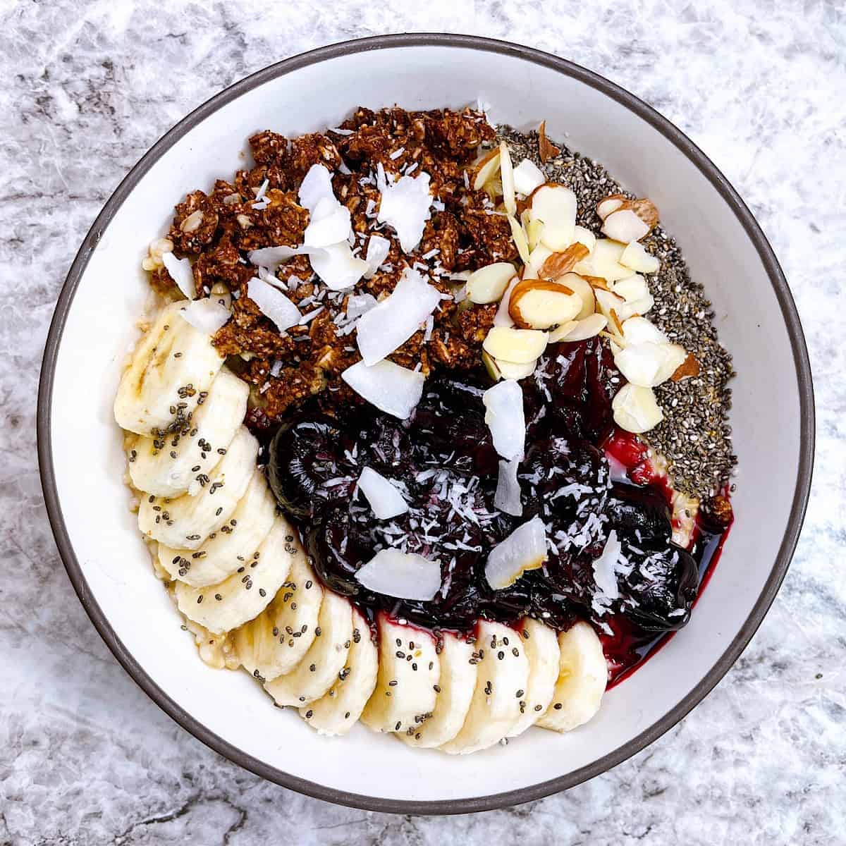 Cherry oats with banana chocolate granola coconut almonds and chia in arranged in bowl