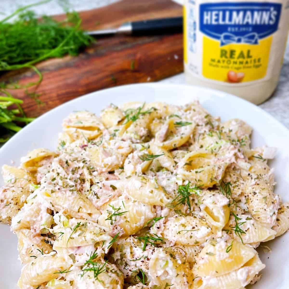 Classic Pasta Tuna Salad with fresh dill a cutting board and Hellman’s mayonnaise in the background