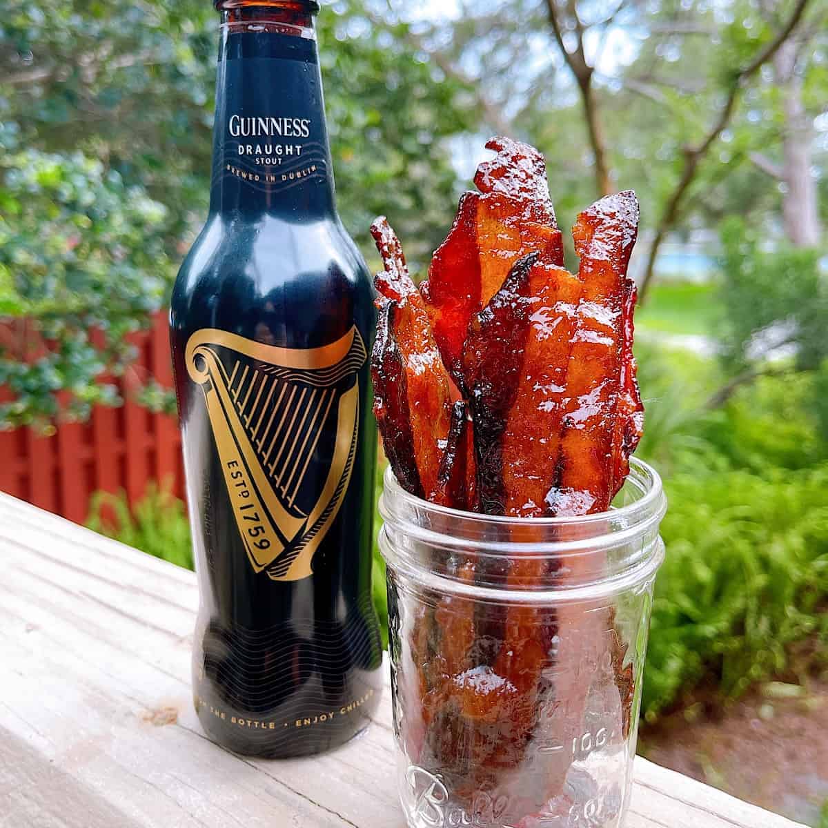 Guinness Candied Bacon​ in a glass jar outside