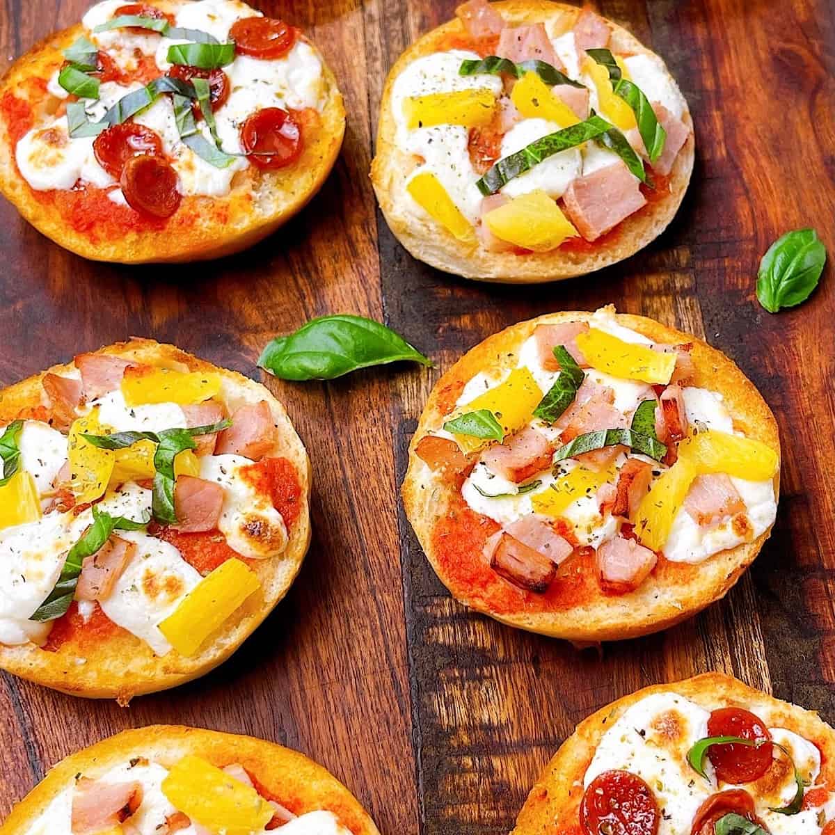 Air Fryer Made Your Way Bagel Bites on wooden cutting board two varieties Canadian bacon and pineapple and pepperoni
