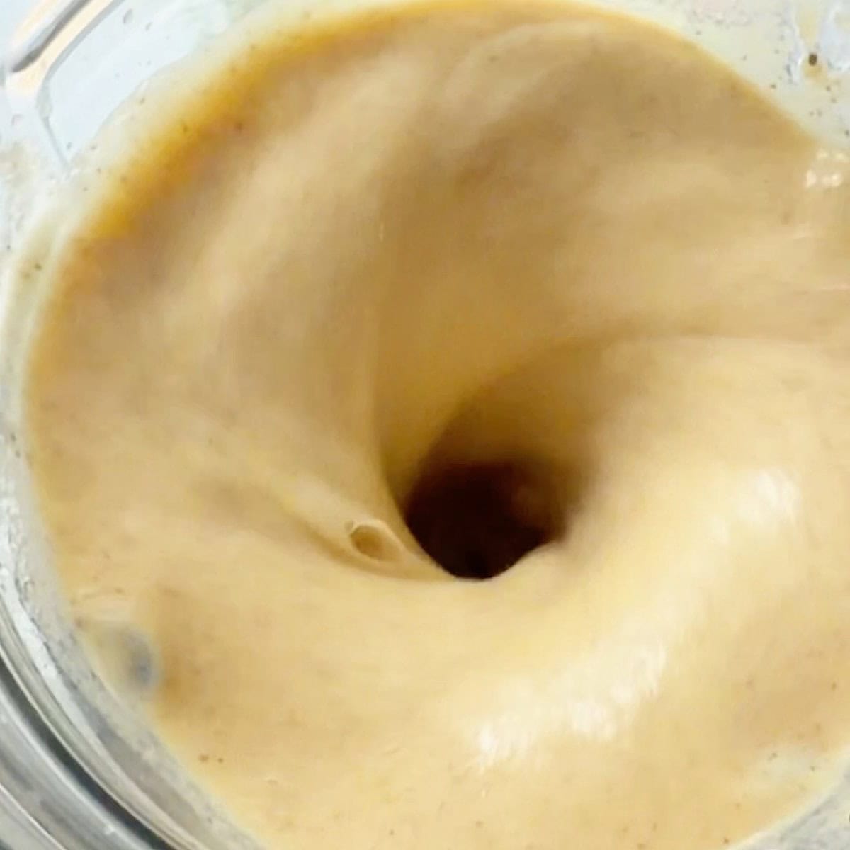 Melon smoothie swirling in blender.