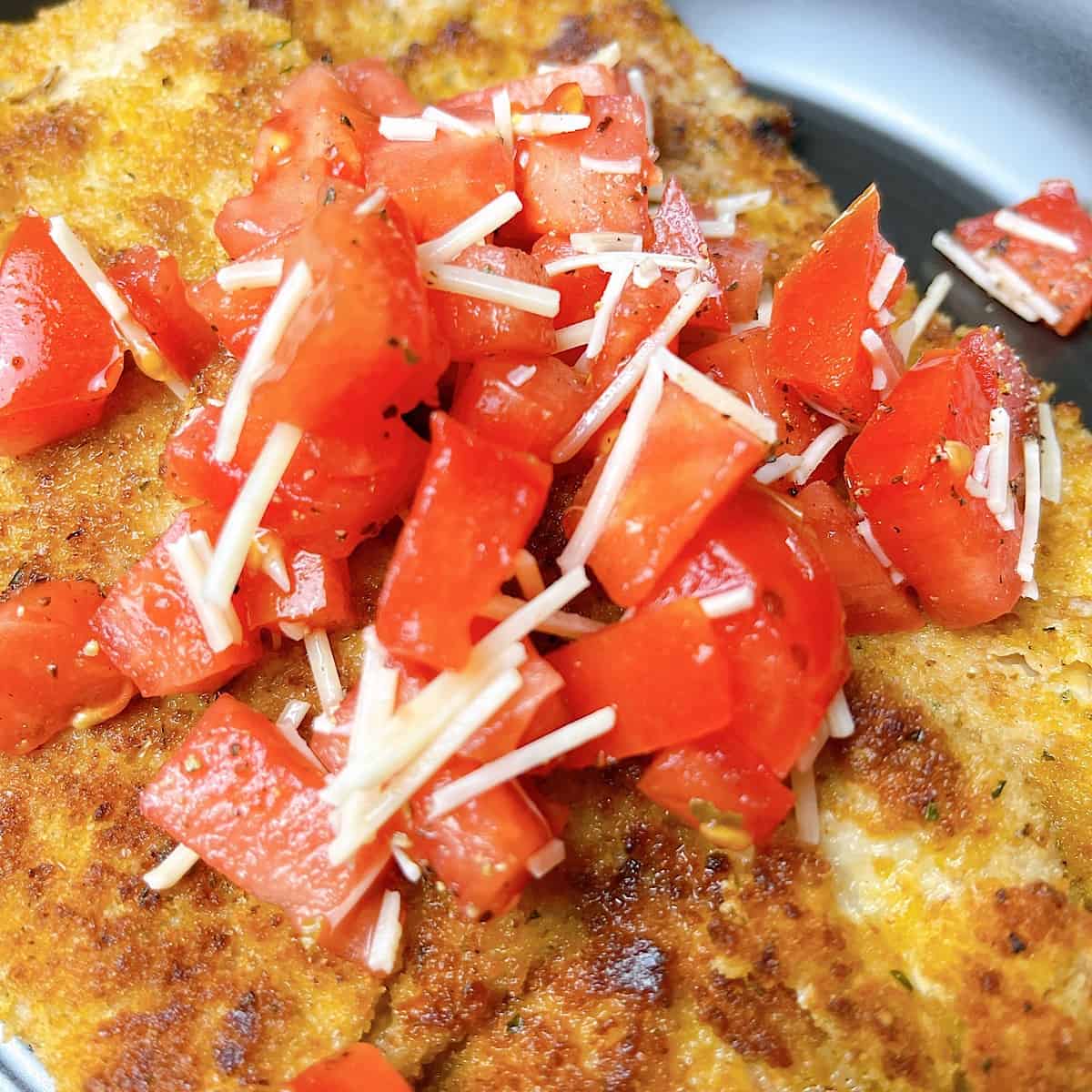 Veal Milanese close up with tomatoes and parmesan