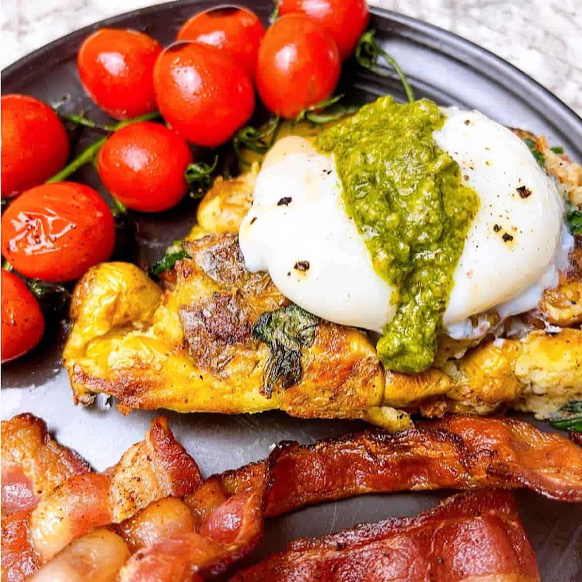 Bubble and Squeak with Pesto Poached Egg and a side of roasted tomatoes and bacon