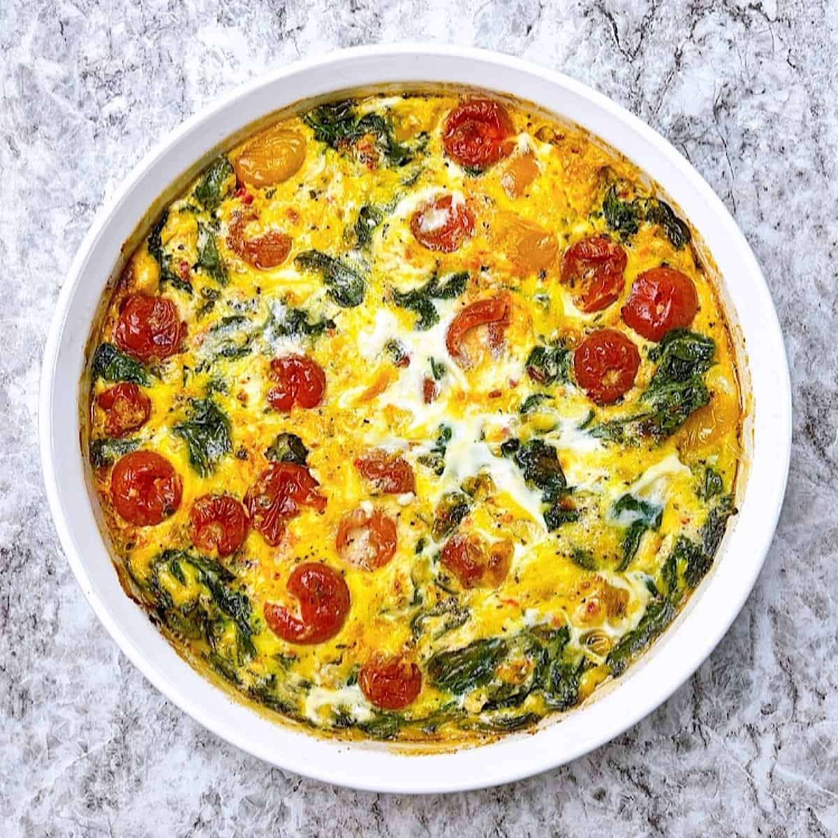 Crustless Spinach Quiche with Roasted Tomatoes and Feta in white dish